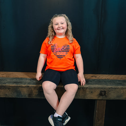 Young girl smiling in Love Cuse heart tee

